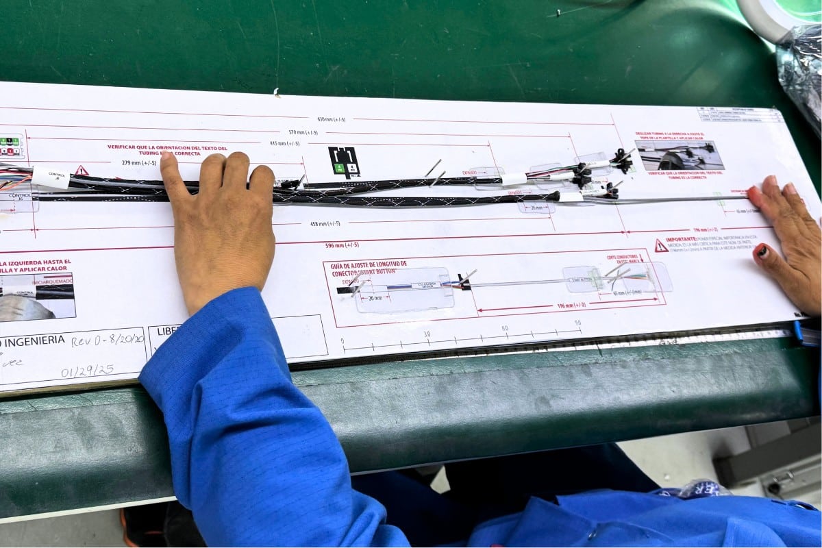 Technicians assemble wire harnesses following detailed layout boards to ensure precise routing and component placement.