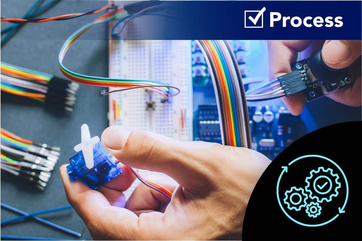 Federal Elec Blog-10 Graphic-02 Hands connecting wires and components on a PCB prototype station, illustrating engineering processes used to prevent component shortages in electronics manufacturing.